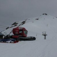 Pistenbully, links die Bergstation des Schlepplifts Fleschboden, dahinter noch etwas höher die Bergstation des Schlepplifts Stafel, April 2009